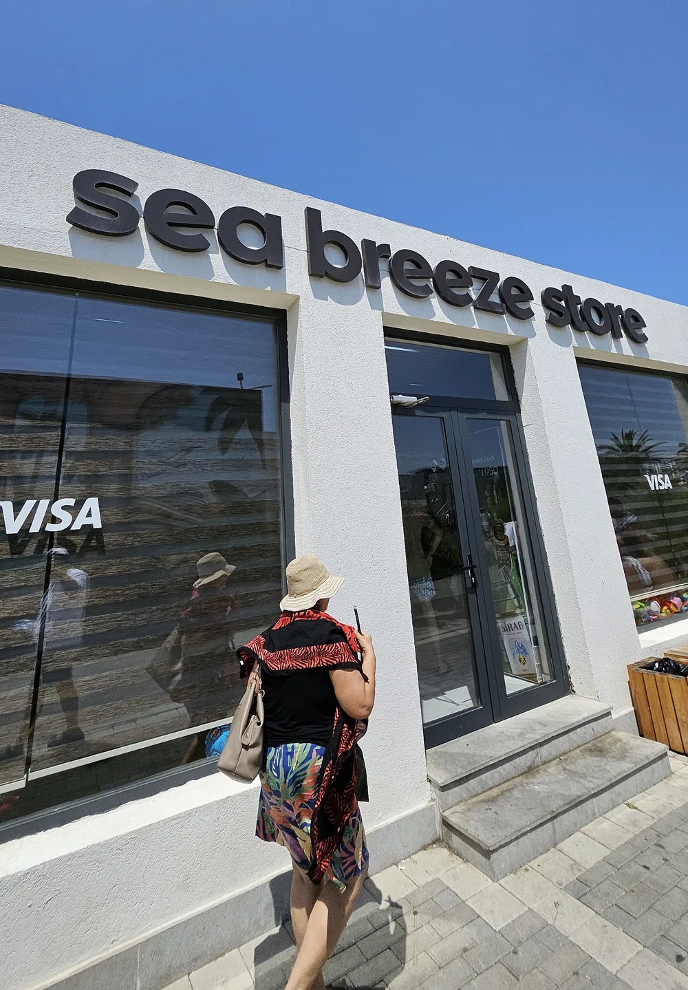 Павильон Sea Breeze Store: тёмные буквы на белом фасаде, витрины с наклейкой VISA
