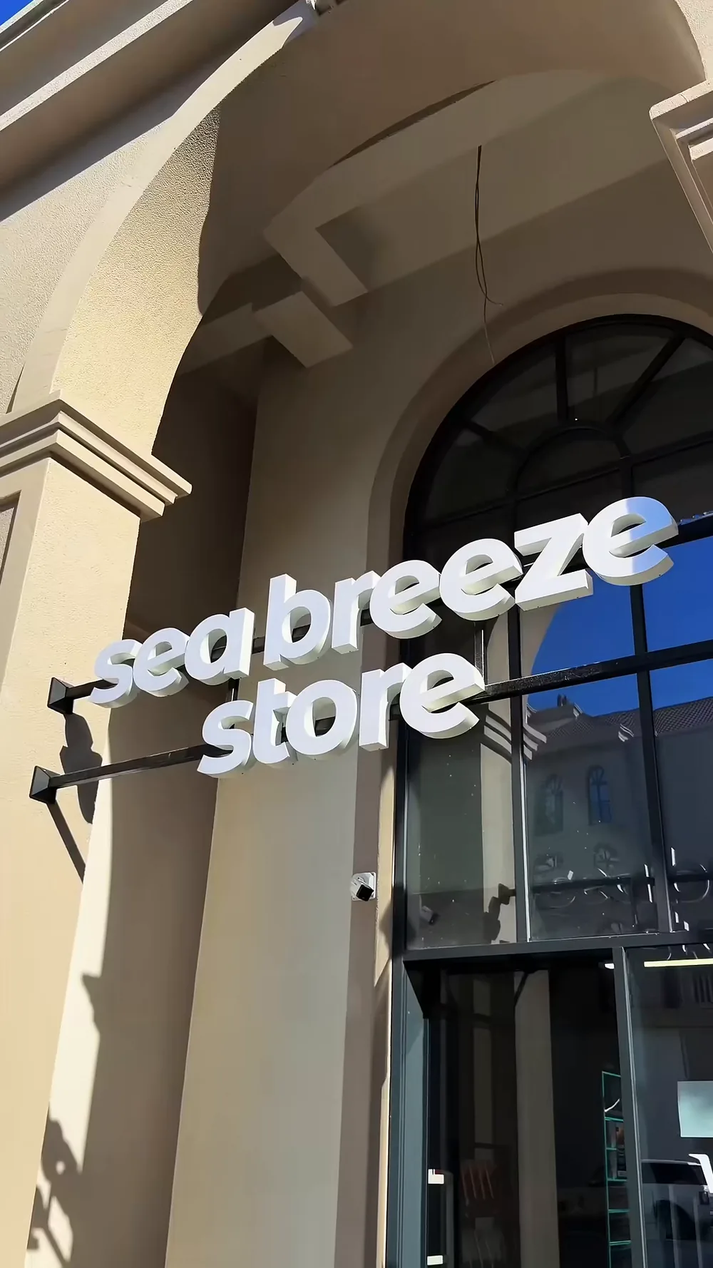 Объёмные белые буквы «sea breeze store» на кронштейне над арочным входом